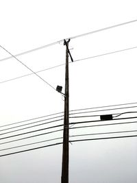 Low angle view of electricity pylon against clear sky
