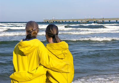 Rear view of friends standing at beach