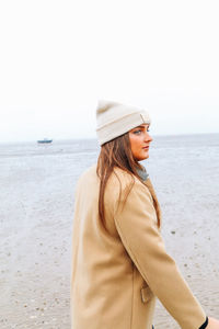 Woman standing at beach against clear sky