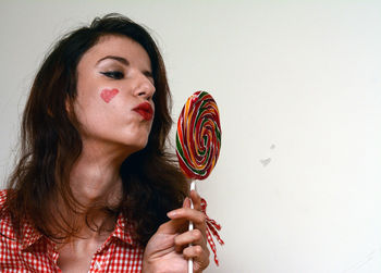 Young woman holding colorful lollipop against white background