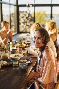 Portrait of happy woman sitting with breakfast on dining table at retreat center