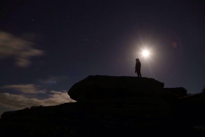 Low angle view of silhouette person standing on mountain against sky