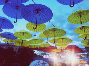 Low angle view of multi colored umbrellas against blue sky