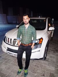 Portrait of young man standing on car