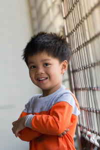 Portrait of cute boy standing against window