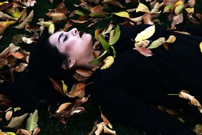 High angle view of young woman lying on leaves