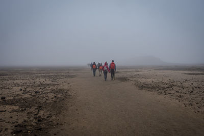 People walking on land against sky