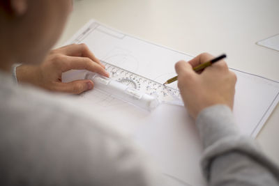 Close-up of architect working over blueprint on table at office