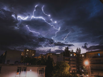 Low angle view of lightning in city against sky at night