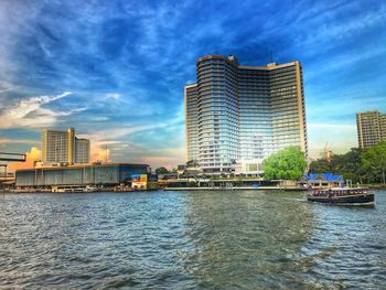 River by buildings in city against sky