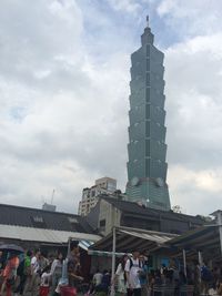 People at amusement park against cloudy sky