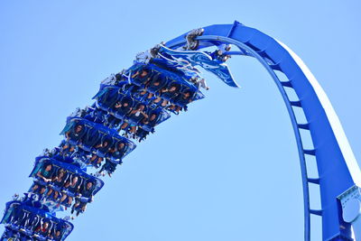 Low angle view of ferris wheel against clear blue sky