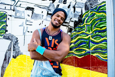 Happy young man standing against graffiti wall