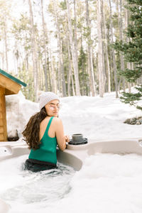 Woman in a hot tub in the winter near a cabin