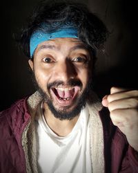 Portrait of smiling young man against black background