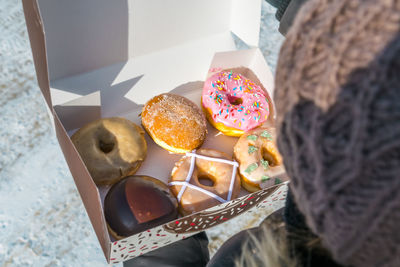 Close-up high angle view of woman holding various donuts in box