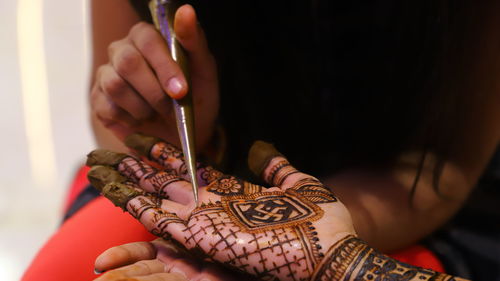 Midsection of woman applying henna tattoo to bride