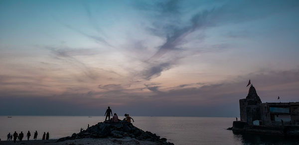 People on sea against sky during sunset