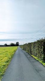 Road amidst field against sky