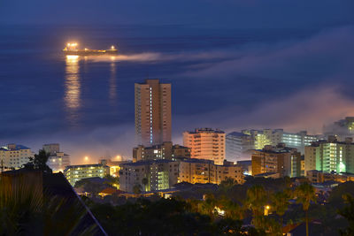 Illuminated cityscape against sky at night