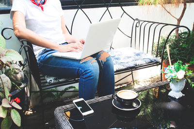 Midsection of man using mobile phone while sitting on seat