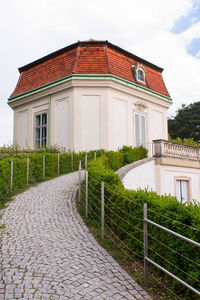 House by footpath against sky in city