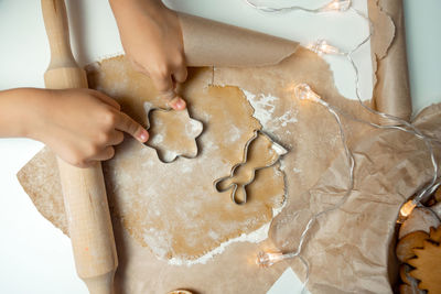 The child's hands make cookies from dough with a mold, the rolling pin lies near the dough with 