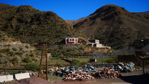 Houses by trees and mountains against clear sky