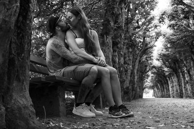 Couple kissing while sitting on bench at park