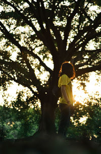 Side view of woman standing by tree
