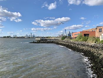 Scenic view of river by buildings against sky