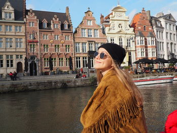 Woman by canal against buildings in city