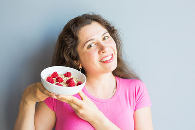 Portrait of smiling woman holding fruit against white background