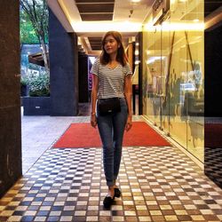 Portrait of smiling young woman standing on tiled floor