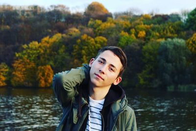 Portrait of young man standing against lake