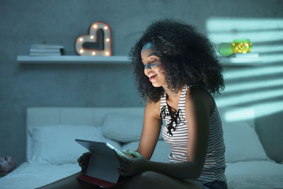 Young woman using mobile phone while sitting on table