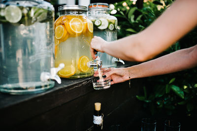 Midsection of woman filling glass from water in jar