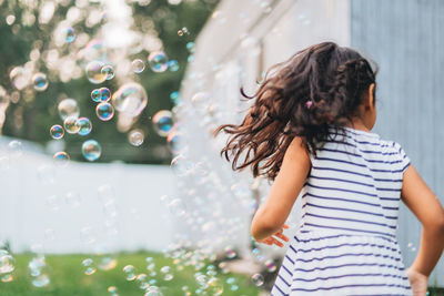 Diverse mixed race pre school age girl at home having fun playing with bubbles 