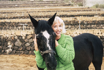 Smiling woman petting horse