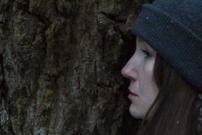 Close-up of woman standing by tree trunk