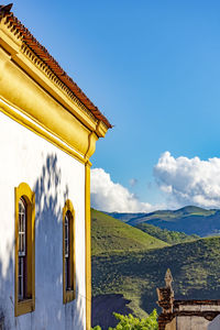 Side of historic colonial church with hills and blue sky