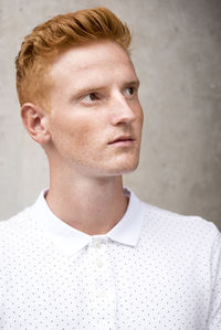 Portrait of young man looking away against wall
