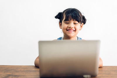 Portrait of smiling girl using laptop on table