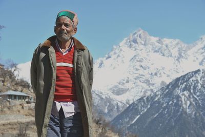 Portrait of smiling man standing on snow covered mountains