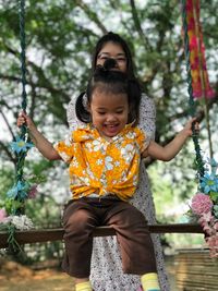 Mother swinging daughter on swing at park