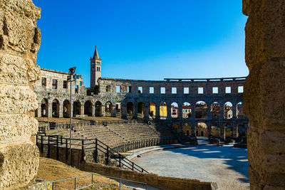 Pula arena with church tower in the background and blue sky