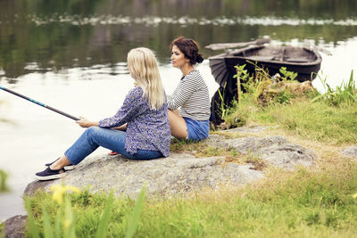 Full length of women fishing while sitting at lakeshore