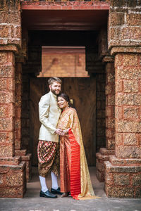 Portrait of couple standing against building