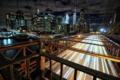 Illuminated railroad tracks in city against sky at night