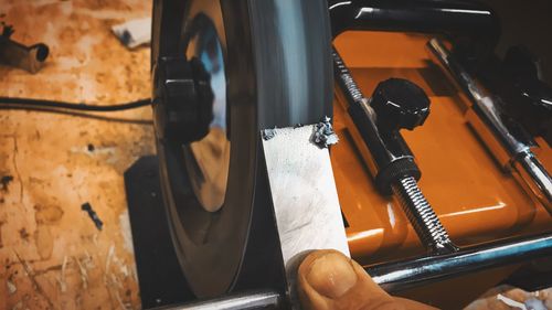 Close-up of finger holding metal by machinery